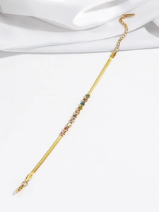 Detail of gold-plated herringbone bracelet with colorful zircon stones on silk background