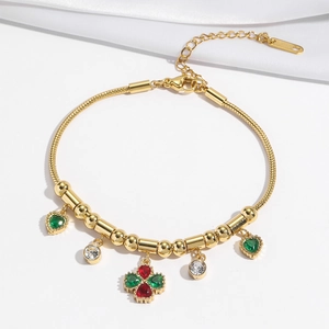 Détail du bracelet en or avec pierres de cœur vertes et trèfle sur fond de soie