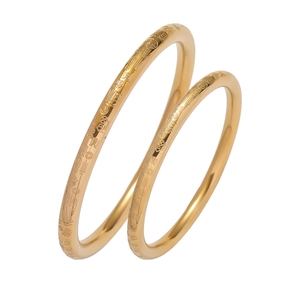 Detail view of two gold titanium steel bangles with Fu character and coin relief patterns