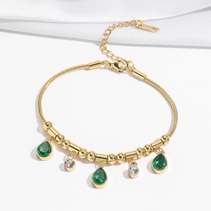 Detail of gold snake chain bracelet with emerald teardrop stones and white cubic zirconia