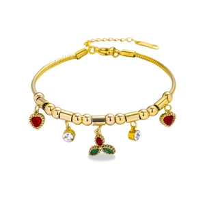 Close-up of golden charm bracelet with red hearts and green zircon berry charms