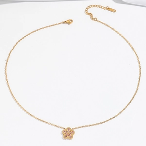 Detailed view of golden necklace featuring a pink zircon flower pendant on white silk