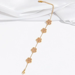 Macro detail of gold-plated bracelet featuring five pink clover charms and K18 engraving