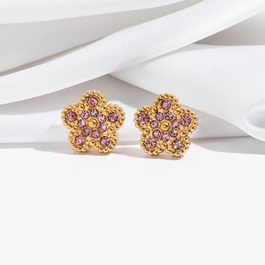 Detailed view of pink crystal flower stud earrings with gold beaded edges on white silk