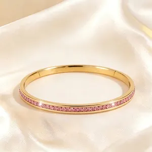 Bracelet jonc en acier titane doré serti de cristaux roses sur fond de soie
