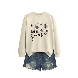 Cream crewneck sweatshirt featuring Let It Snow typography and blue distressed denim shorts
