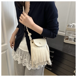 Detailed view of beige PU leather crossbody bag with long fringes and round buckle