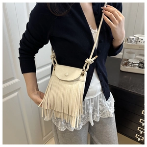 Close-up of cream white PU leather crossbody bag with bohemian tassel design details