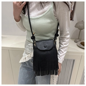 Detail of vintage black crossbody bag featuring long fringes and textured faux leather