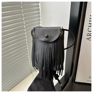 Detail of black crossbody bag with long fringes and lychee texture on the leather surface