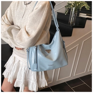 Détail du sac cabas en similicuir bleu clair avec triangle en métal et gland décoratif