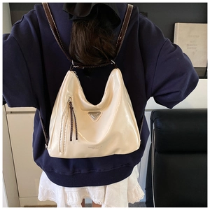 Détail du sac en cuir verni beige brillant avec logo triangulaire et bandoulière brune