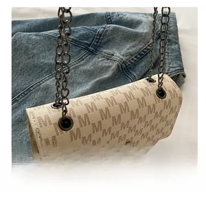 Detail of white leather chain bag with brown M-pattern and dark metal twist lock