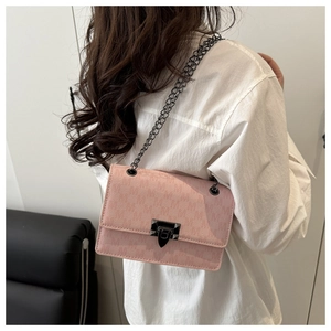 Pink suede-textured crossbody bag with black chain strap shown on model's shoulder