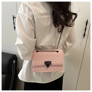 Detail of light pink crossbody bag with M-embossed pattern and gunmetal chain strap
