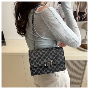Side view of monogram printed crossbody bag with silver chain strap and metal clasp
