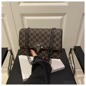 Close-up of retro brown leather shoulder bag with monogram print and metallic chain strap
