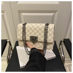 Detail of cream crossbody bag featuring all-over M letter print and chunky metal chain strap