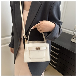 Close-up of white square handbag showing cross-grain texture and gold turn-lock closure