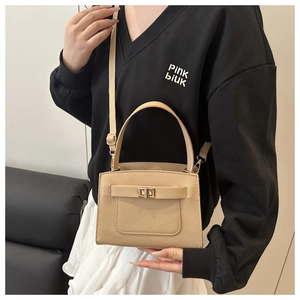 Close-up of beige crossbody square bag with metal turn-lock and adjustable strap