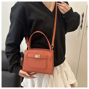 Detail of coral red crossbody bag featuring Saffiano texture and golden turn-lock