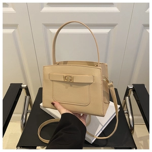 Detail of minimalist beige handbag showing cross-grain leather and golden turn-lock
