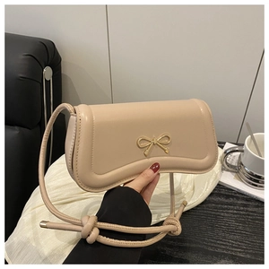Detail of beige hobo bag with gold bow buckle and stylish knotted shoulder strap