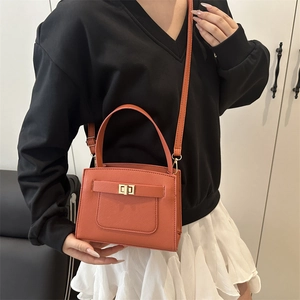 Minimalist orange crossbody square bag with gold turn-lock and adjustable shoulder strap