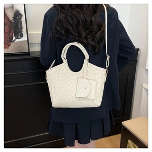 Close-up of stylish white monogram tote bag with matching mini pouch on a model