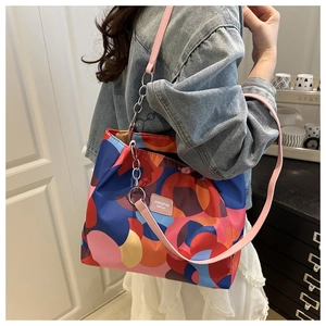 Detail of colorful geometric tote bag featuring pink leather strap and chain attachment