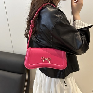 Chic rose pink underarm bag featuring a gold metal bow clasp on a soft leather surface