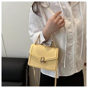Close-up of bright yellow mini crossbody bag featuring a golden oval twist-lock buckle