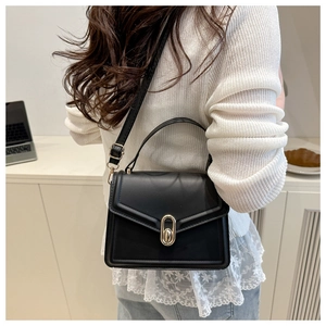 Close-up of elegant black leather handbag featuring a golden oval twist lock and handle