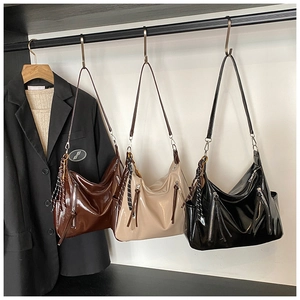 Trois sacs hobo en cuir brillant caramel, crème et noir avec des détails zippés en métal