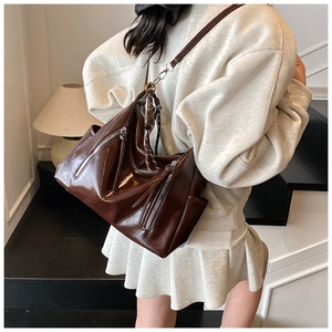 Detailed side view of large dark coffee patent leather tote bag with stylish zipper accents