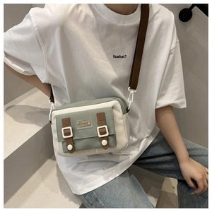 Détail du sac bandoulière en toile avec patchwork vert et blanc et lanières brunes