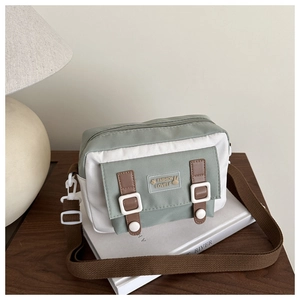 Detail van groene canvas crossbodytas met modieuze patch en verstelbare riem