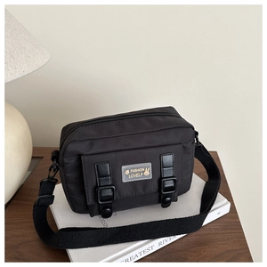 Detailopname van zwarte canvas schoudertas met decoratieve gespen en verstelbare riem