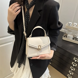 Minimalist cream white leather handbag with gold buckle shown in an elegant home setting