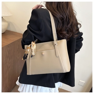 Close-up of khaki tote bag featuring a decorative silk scarf tied on the handle