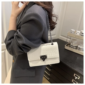 White croc-embossed chain shoulder bag with a metal lock worn with a grey blazer