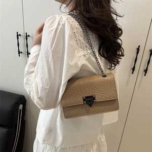 Light brown woven chain shoulder bag with V-shaped metal lock worn by a model