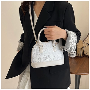 Detailed view of white shell-shaped handbag with lace texture and golden metal zipper