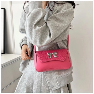 Detail of rose pink handbag with woven texture flap and silver metal bow buckle charm