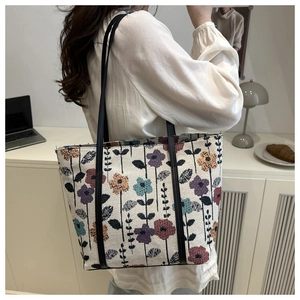 Sac fourre-tout à fleurs en jacquard porté à l'épaule par un mannequin en intérieur