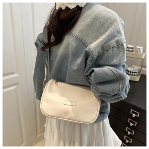 Cream white PU leather crossbody bag worn by a model in a casual home setting