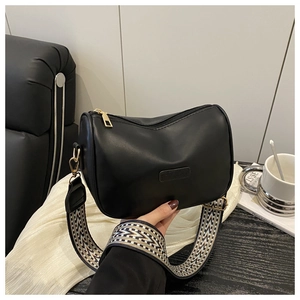 Detail of black matte pillow bag with geometric woven strap and gold hardware
