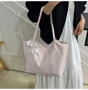 Detail of pink tote bag with delicate lace trim and pearl bow charm for daily commuting