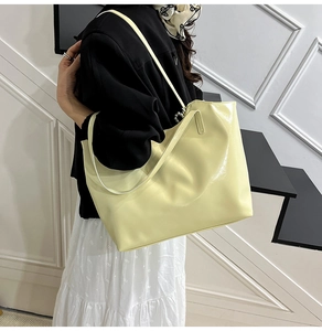 Close-up of cream glossy patent leather tote bag showing shiny finish and slim straps