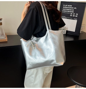 Close-up of silver metallic tote bag with decorative pearl and lace bow charm
